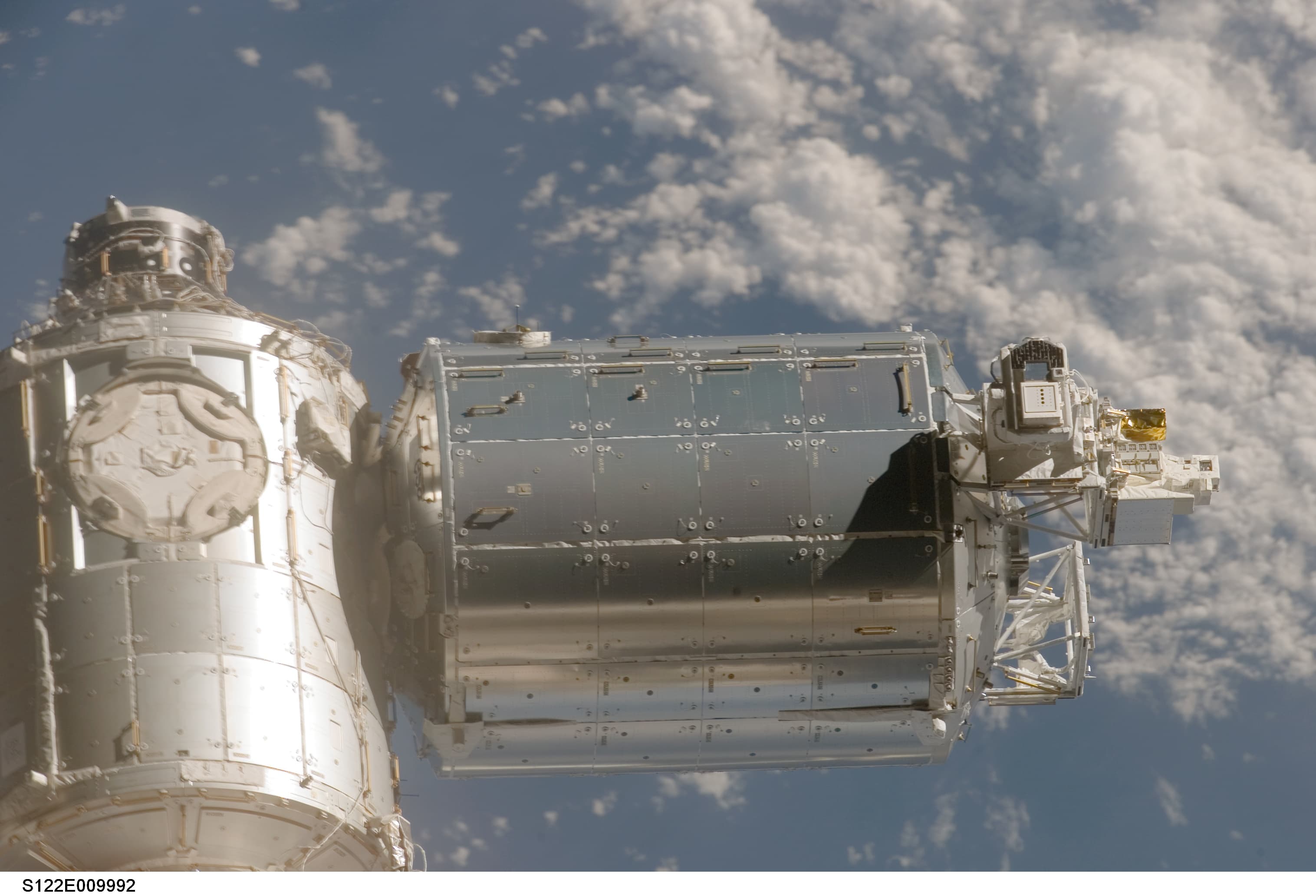 Columbus laboratory’s cylindrical exterior attached to Harmony above clouds on Earth