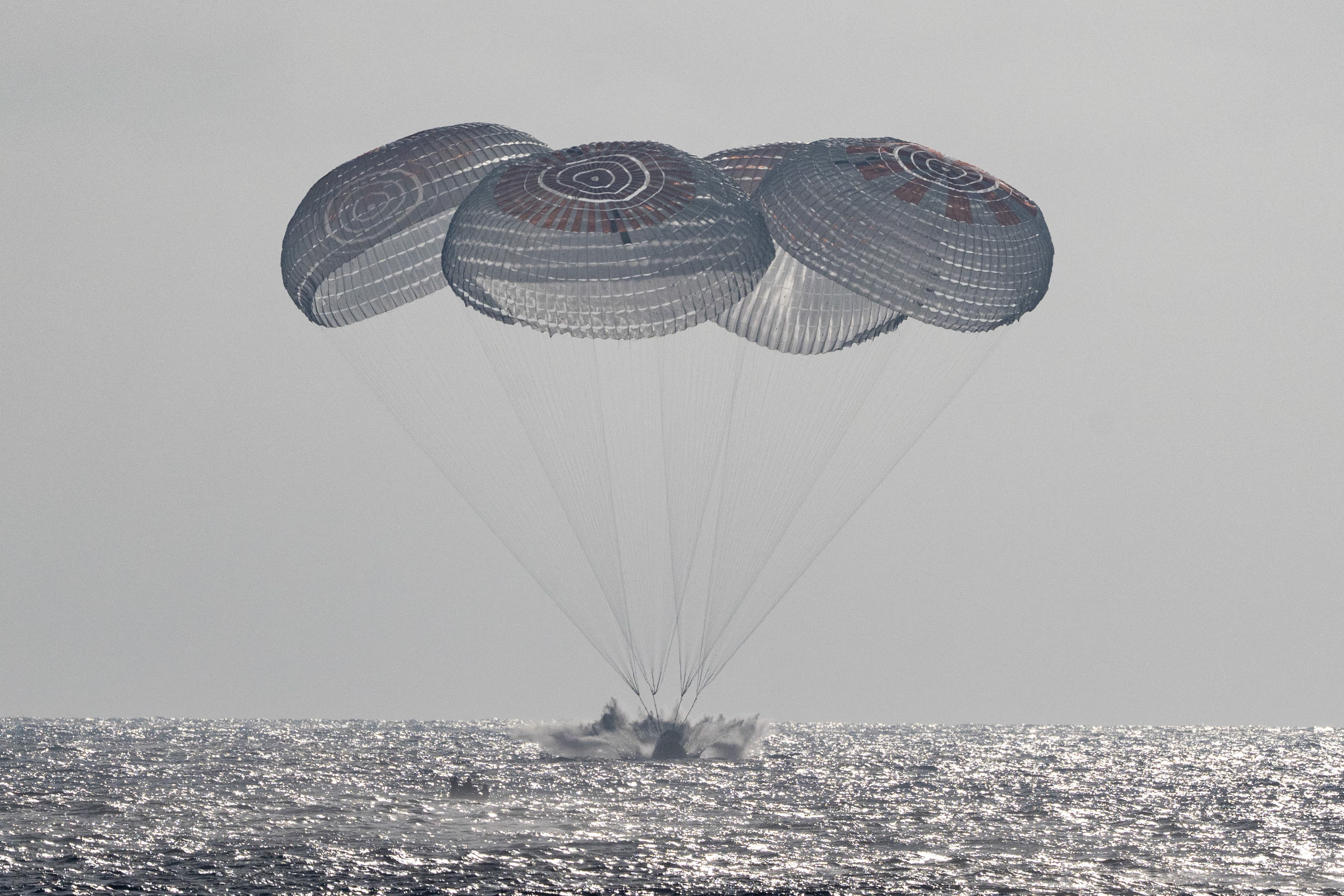 Dragon Freedom touches the ocean in a splash beneath four deployed parachutes