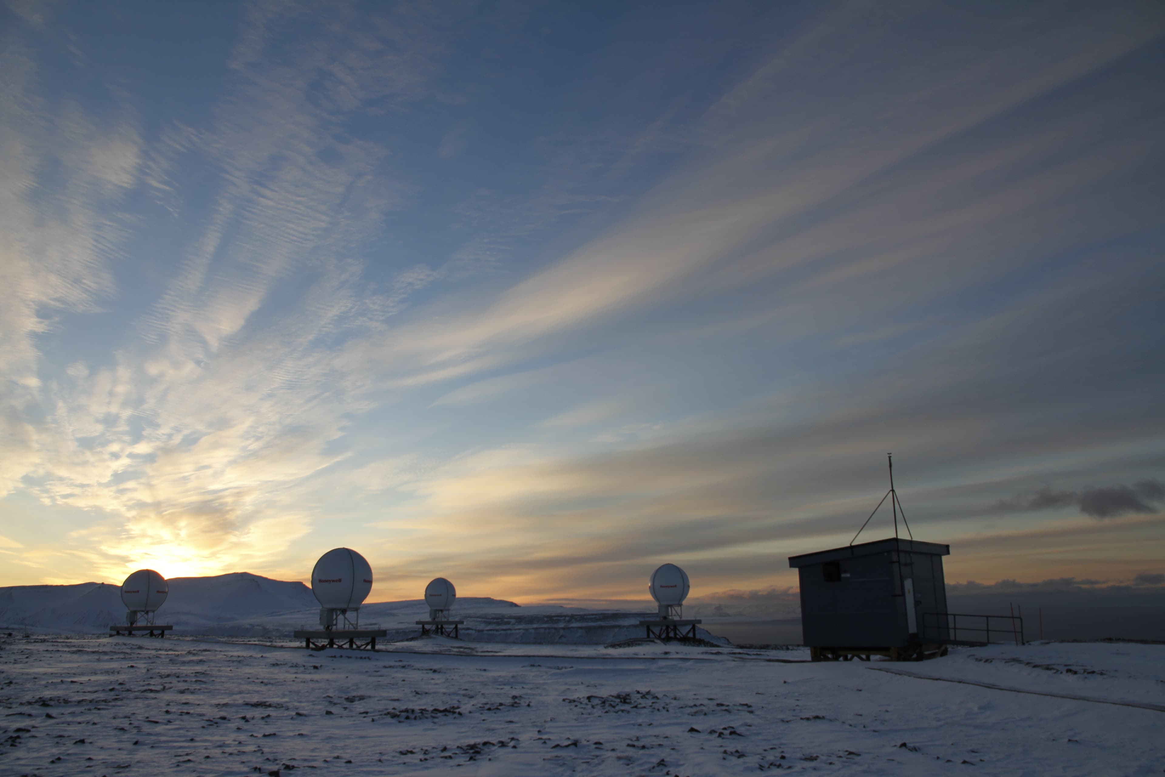 Four dish antennas and a small building on snow-covered ground at the Svalbard rescue terminal