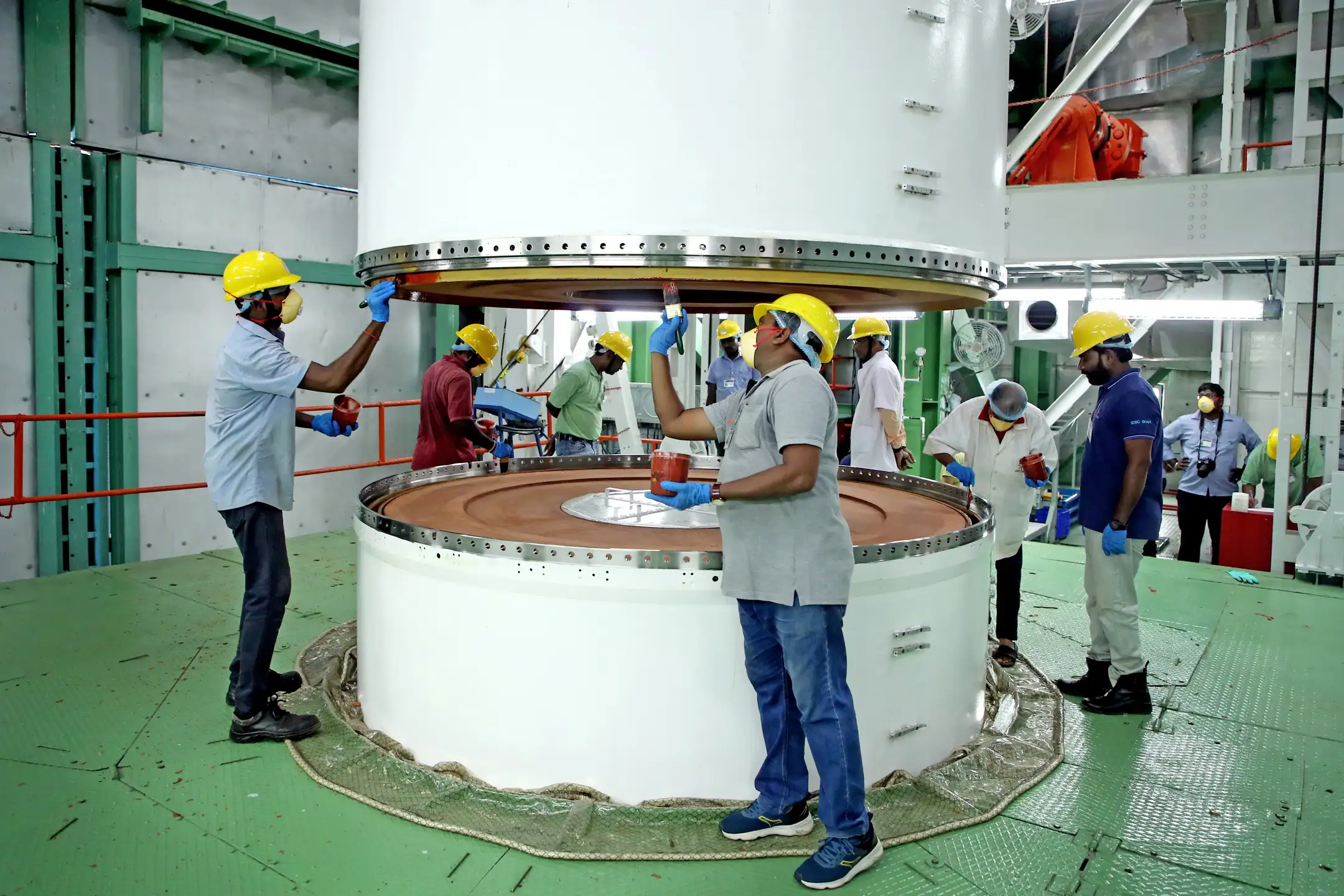 Technicians work around cylindrical sections of PSLV-C59 during pre-launch integration