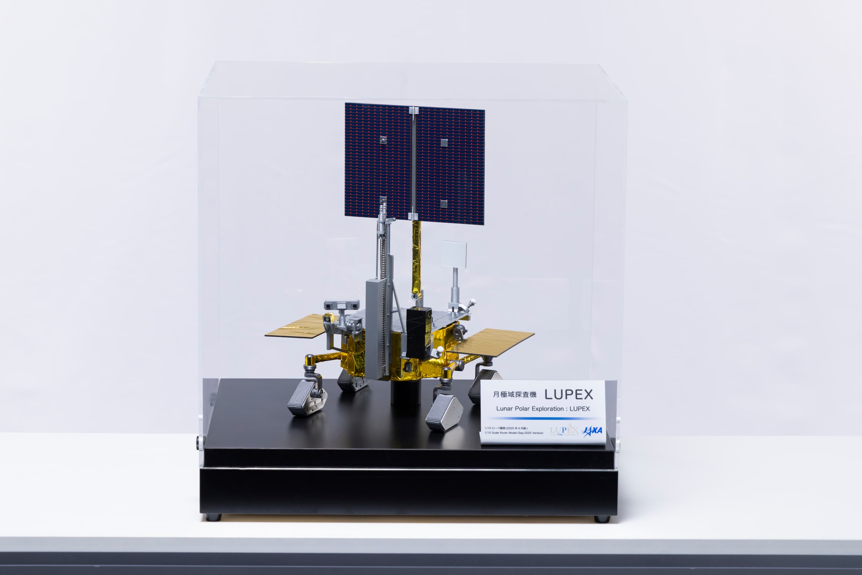 Scale model of the LUPEX lunar rover in a clear display case, with wheels, a mast and a raised solar panel