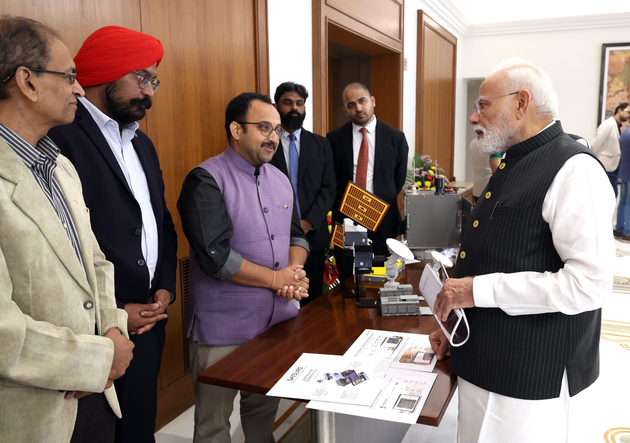 Prime Minister Narendra Modi looking at a space-technology display with startup leaders in a meeting room