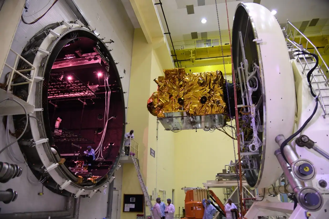 NVS-02 navigation satellite suspended beside an open thermal-vacuum test chamber at an ISRO facility