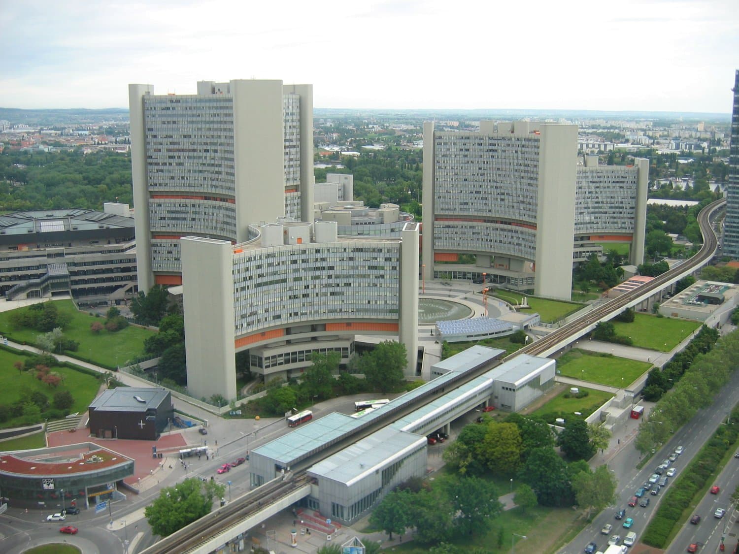 Towers of Vienna International Centre beside an elevated railway and surrounding city buildings
