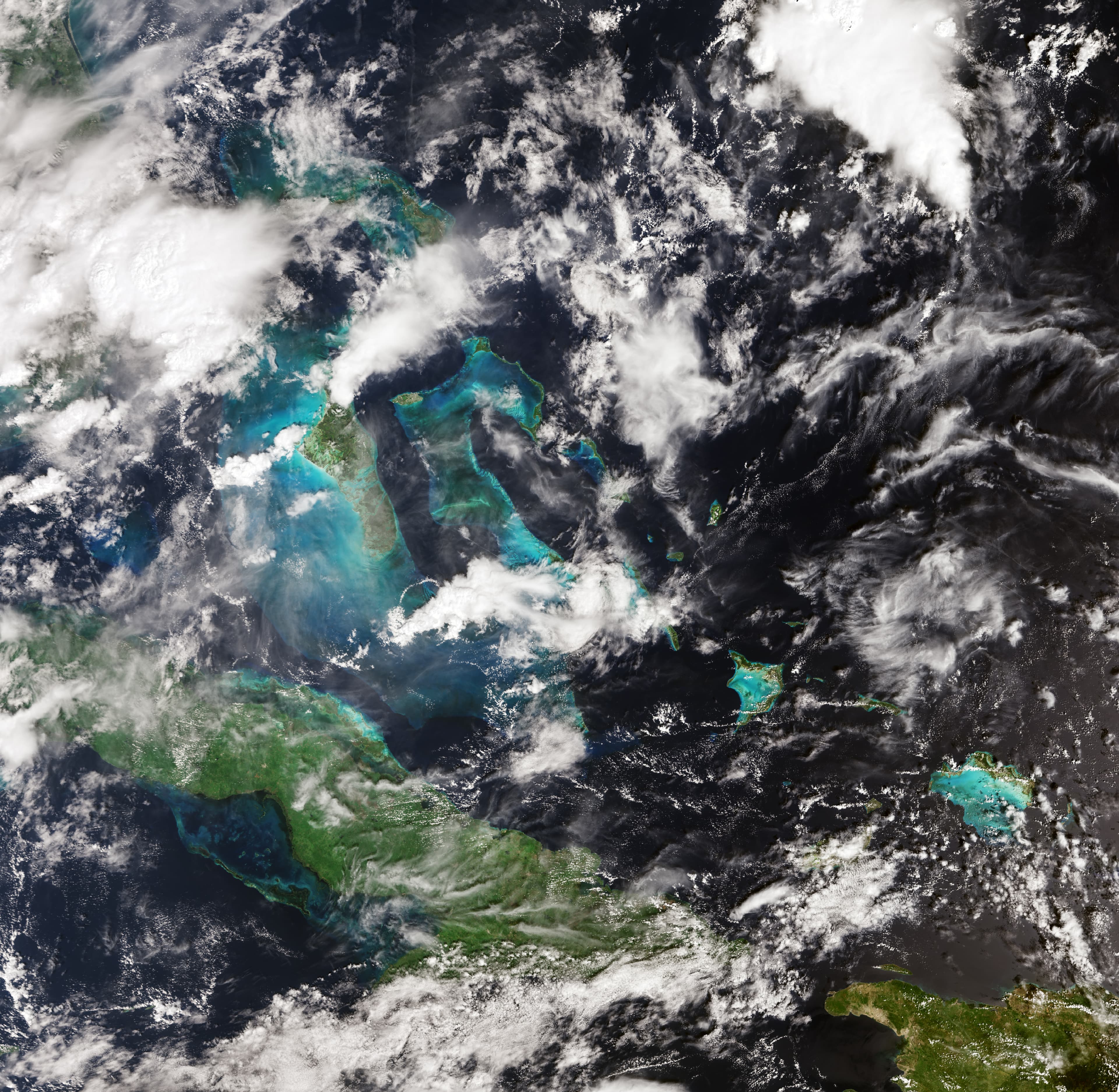 Clouds over Cuba and the Bahamas, with turquoise shallow waters and dark open ocean