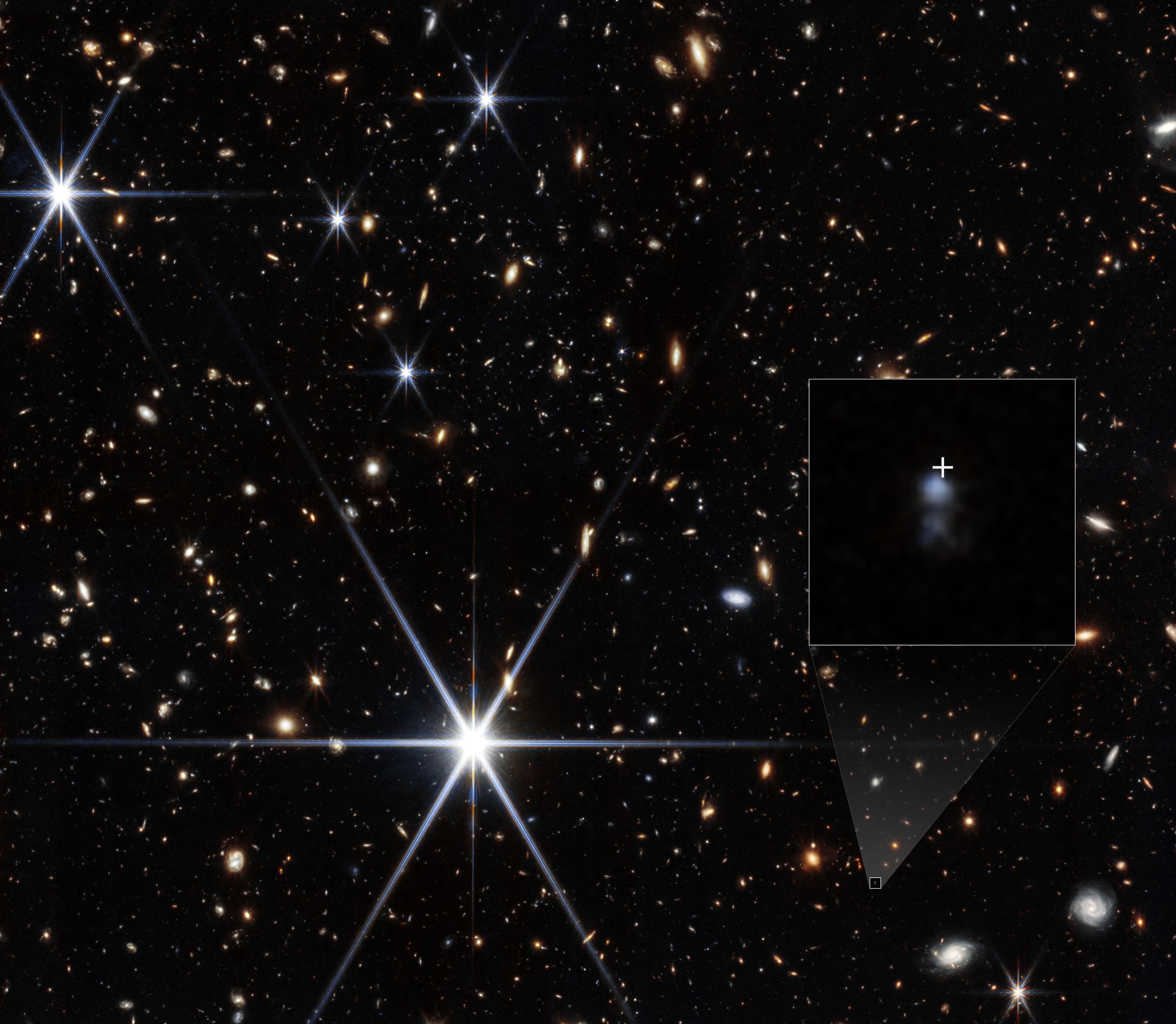 A Webb galaxy field with an enlarged inset showing two blue clumps and a white cross marking the radio-burst position